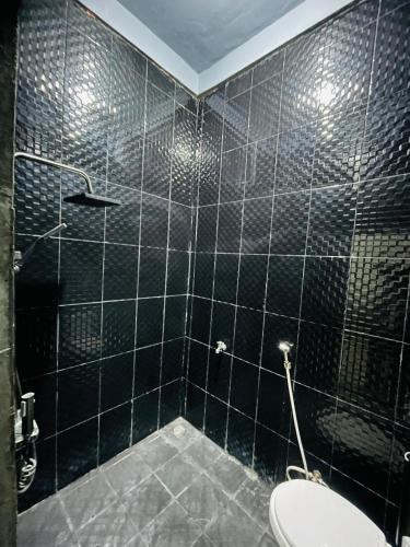 a black tiled bathroom with a toilet and a shower at AFWA Surf and Stay in Selong Belanak