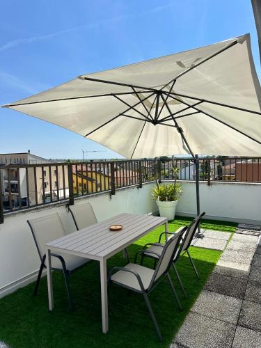 a table and chairs with a large umbrella on a balcony at Catullo Loft Near Verona in Dossobuono
