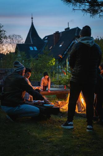 a group of people sitting around a fire at Perła Sudetów by Stay inn Hotels in Karpacz