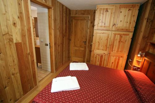 a bedroom with a red bed with two towels on it at Champoluc Apartment in Champoluc