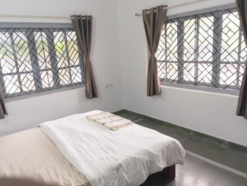 a bed in a room with two windows at Peace Villa with pool in Murud