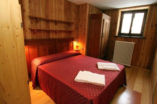 a bedroom with a red bed with two towels on it at Champoluc Apartment in Champoluc