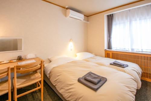 two beds in a room with a desk and a television at べっどぷらす in Wakkanai