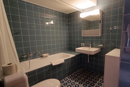 a blue tiled bathroom with a tub and a sink at Majestic 424 in Bagnes