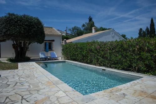 a swimming pool in front of a house at Charmante petite maison à Corfou in Pelekas