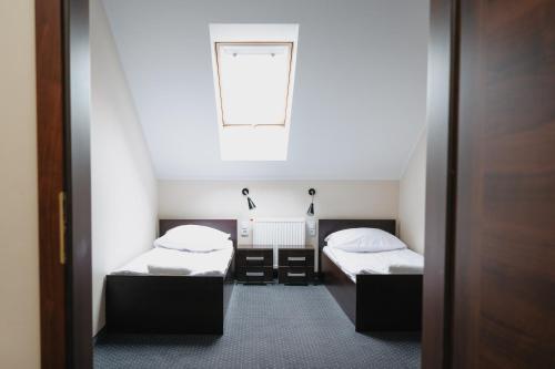 two beds in a small room with a window at Potocki Dwór in Jędrzejów