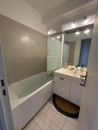 a bathroom with a tub and a sink and a mirror at Studio cabine, vue mer, piscine in Saint-Cyprien-Plage