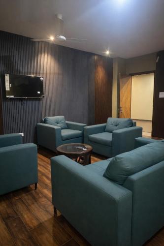 a waiting room with blue couches and a flat screen tv at Cassette Inn in Zahirābād