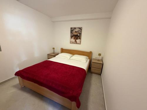 a bedroom with a bed with a red blanket at White stone house in Bigova
