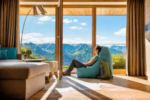 a woman sitting on a couch in front of a large window at Panorama Alm in Jochberg
