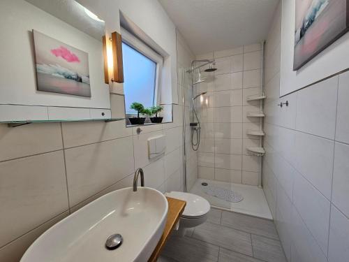 a white bathroom with a sink and a toilet at Ferienwohnung "Haggi" 35672 in Uplengen