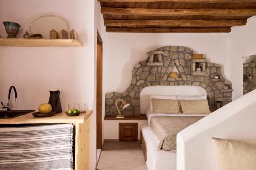 a bedroom with a bed and a stone wall at Infinito Boathouse Milos in Agia Irini Milos