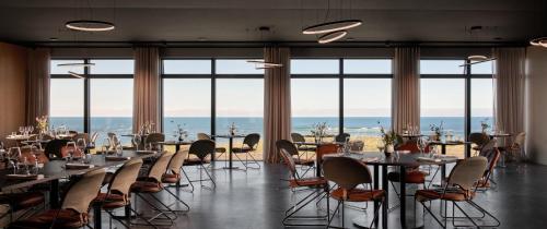 a dining room with tables and chairs and windows at Black Sand Hotel in Ölfus
