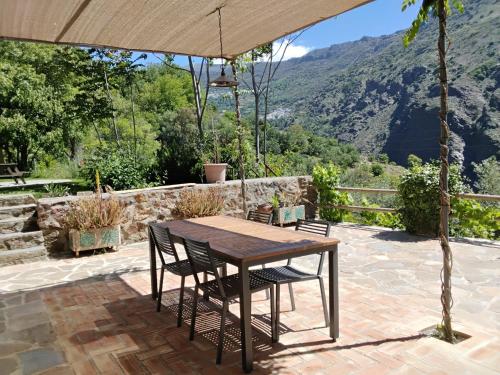 a table and chairs under an umbrella on a patio at Cortijo De Los Abuelos in Pampaneira