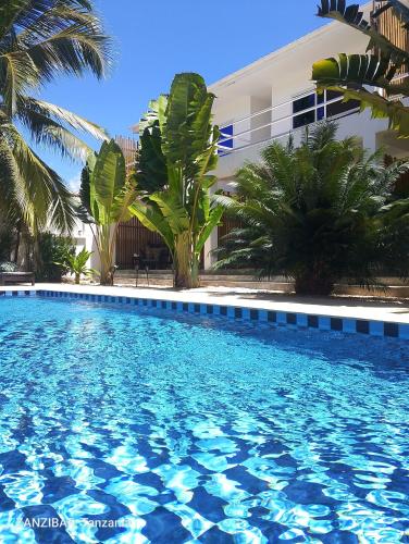 a large blue swimming pool in front of a building at Aurora Boutique Hotel Jambiani in Jambiani