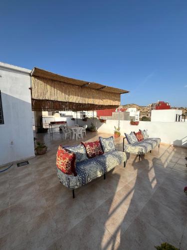 a patio with two couches and a table and chairs at Atlantic view Tamraght 1 in Tamraght Ou Fella