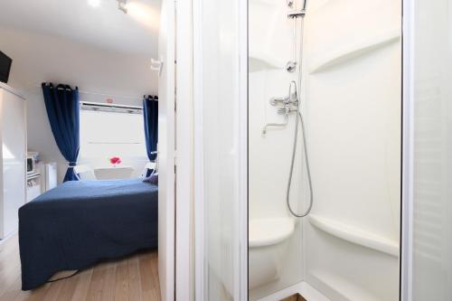 a bathroom with a shower and a bed and a toilet at Couette et café in Arradon