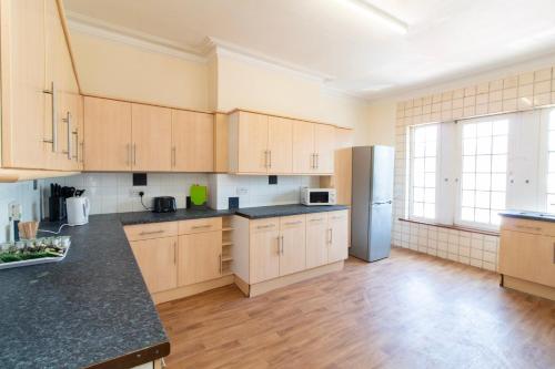 a large kitchen with wooden cabinets and a refrigerator at Room 2 - Brookvale Guest House in Southampton