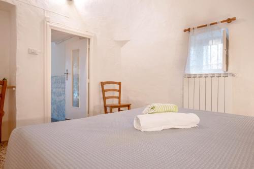 a white bedroom with a bed with a towel on it at Trullo Petronella in Cisternino