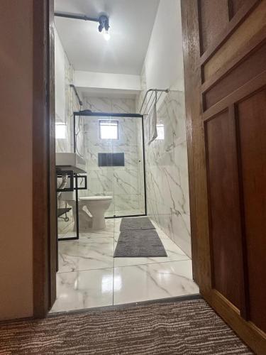 a bathroom with a shower and a toilet and a sink at Pousada Central Araquari in Araquari