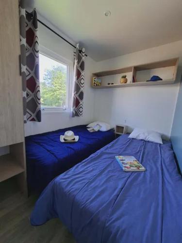 a bedroom with two beds with blue sheets and a window at Camping Le Chassezac in Sampzon