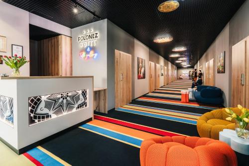 a lobby with orange and blue chairs and a corridor at Hotel Polonez in Krakow