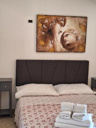 a painting hanging above a bed with towels on it at Relax in Maremma tra Saturnia e Argentario in Pancole