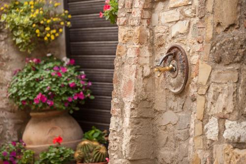 a stone wall with a faucet and flowers at Palazzo Malaspina B&B in Tavarnelle in Val di Pesa