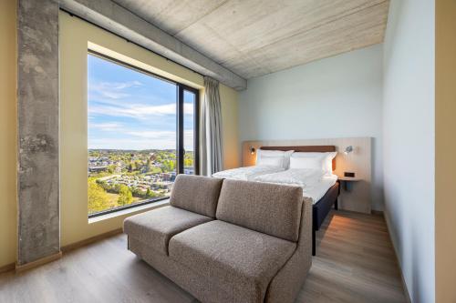 a bedroom with a bed and a chair and a window at Comfort Hotel Grimstad in Grimstad