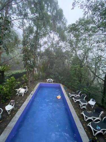 a blue swimming pool with chairs and a group at Villa Concepcion Staycation by ngb in Real