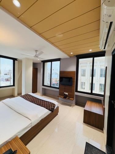 a bedroom with a bed and a tv and windows at La Casa Residency in Lucknow