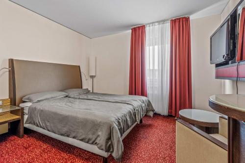 a bedroom with a bed and a flat screen tv at City Best Autobahnhotel Stolper Heide in Berlin
