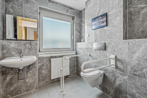 a bathroom with a sink and a toilet and a window at City Best Autobahnhotel Stolper Heide in Berlin