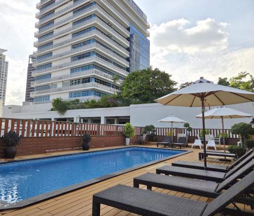 a swimming pool with chairs and an umbrella and a building at True Siam Rangnam Hotel in Bangkok