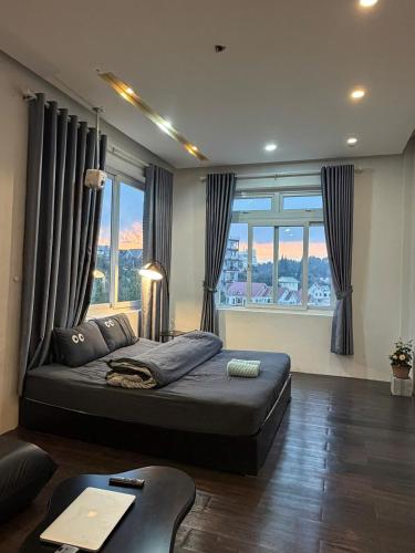 a bedroom with a large bed in front of windows at MiMo Homestay Đà Lạt in Xuan An