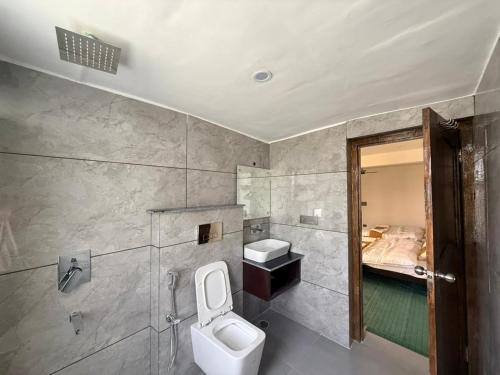 a bathroom with a toilet and a sink and a bed at Natures View Residency in Hundar