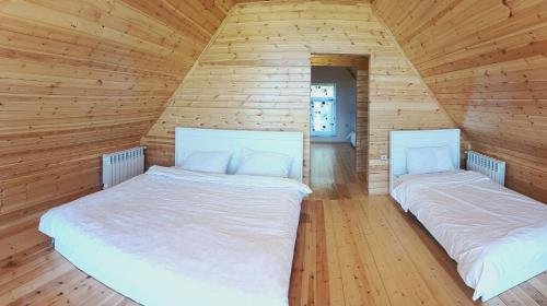 two beds in a room with wooden walls at Shahdag A-Frame in Qusar