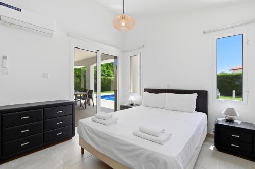 a white bedroom with a bed and a mirror at Bungalow Casa Bella by Ezoria Villas in Coral Bay