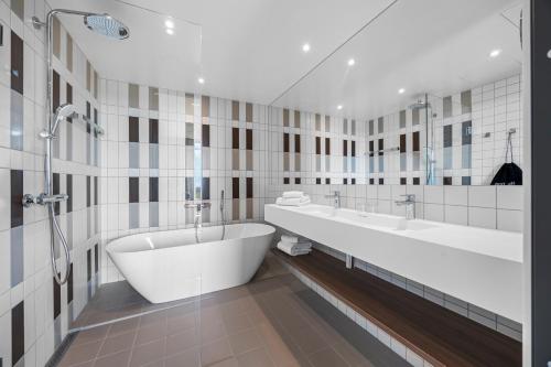 a bathroom with two sinks and a bath tub at Comfort Hotel Grimstad in Grimstad