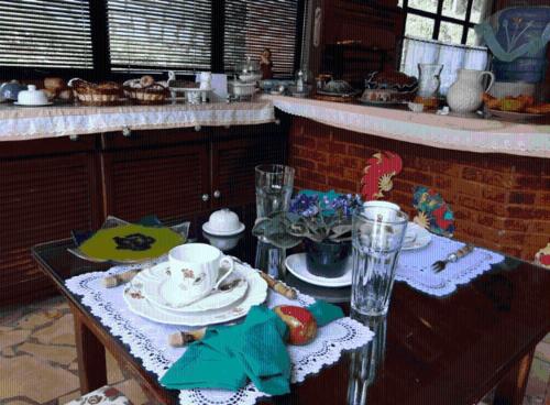 a table with plates and cups on it in a kitchen at Pousada Romântica Serra da Mata in Penedo