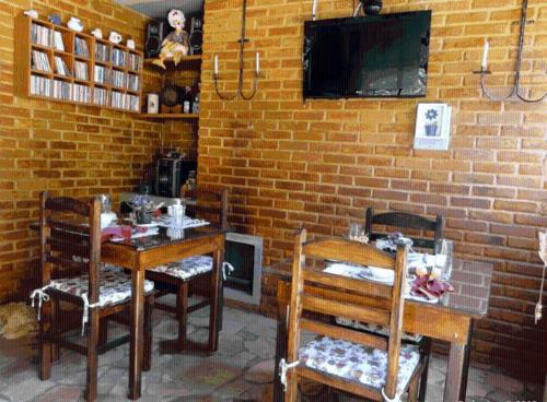 a room with two tables and two chairs and a tv at Pousada Romântica Serra da Mata in Penedo