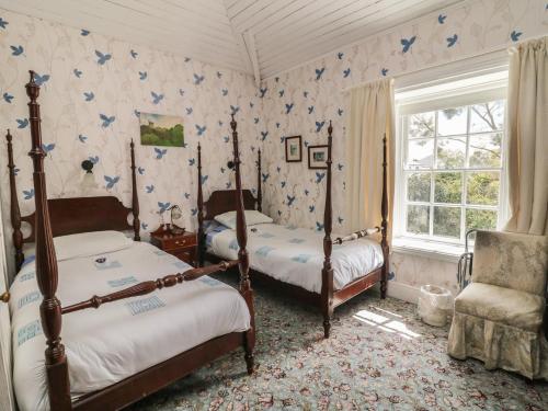 a bedroom with two beds and a chair and a window at Cairbre House in Dungarvan