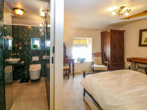 a bedroom with a bed and a bathroom with a sink at Bargate Cottage in Castleton