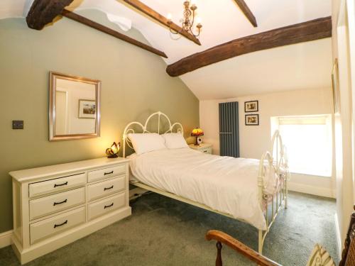 a bedroom with a bed and a dresser and a mirror at Bargate Cottage in Castleton