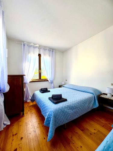 a bedroom with a bed with a blue blanket and a window at Casa Furlan in Calalzo