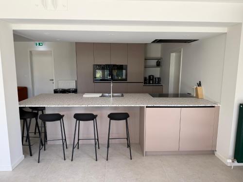 a kitchen with a island with bar stools at De Villadroom in Hasselt