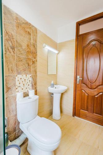 a bathroom with a toilet and a sink at Cytonn unique suits in Ruaka