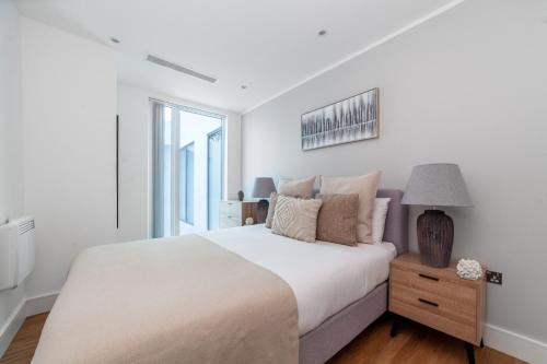 a white bedroom with a bed and a window at Modern 1Bed Flat in Ealing Near Tube & Shops in Ealing