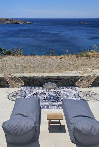 a patio with a couch and chairs and the ocean at Aenya Kythnos Villas in Kithnos