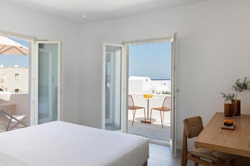 a bedroom with a bed and a table and a balcony at Viva Nove Suites in Kamari